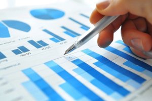 Close-up of a hand analyzing a business chart with a pen.