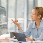 Businesswoman working on a computer with data analytics on screen.