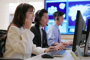 Team of customer service representatives working at computers in a high-tech office.