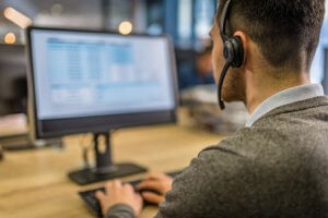 Close-up of a man working with a headset in front of a computer.