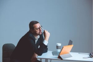 Pensive businessman sitting at a desk with a tablet.