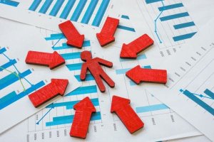 Red arrows pointing to a wooden human figure on a background of financial charts.