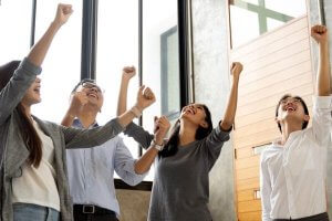 Team celebrating success with raised hands in an office.