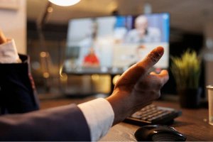 Close-up of a hand gesturing during a virtual meeting.