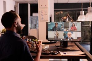 Man participating in a virtual team meeting on a computer screen.