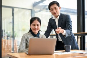 A male mentor guiding a female colleague at work.