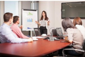 A woman presenting data on a flip chart during a meeting