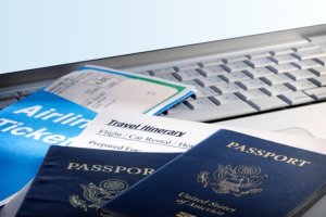 Travel documents including passports and airline tickets on a laptop.