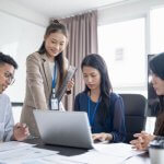 Team of professionals collaborating around a laptop in an office.