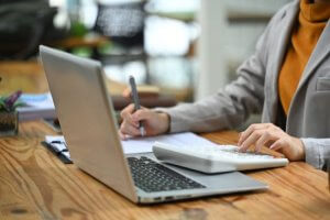 Person using calculator and laptop for work