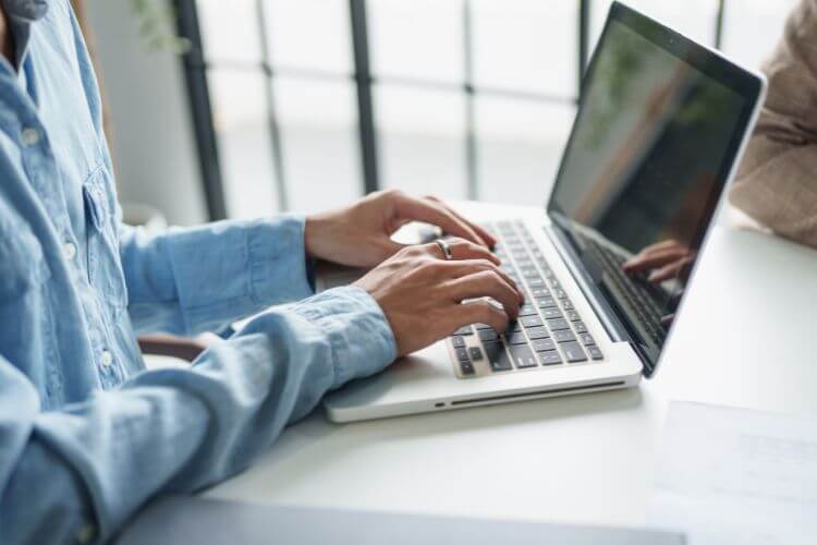 A person focused on typing on a laptop computer, with hands positioned on the keyboard.