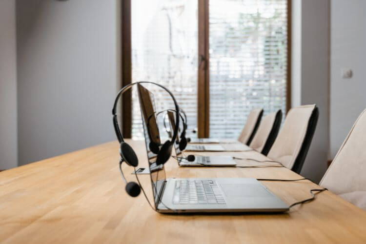 A conference room featuring a laptop and a headset on a table, ready for a virtual meeting.