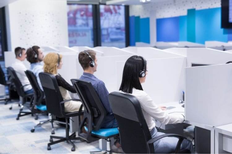 Call center employees working with headsets in office cubicles