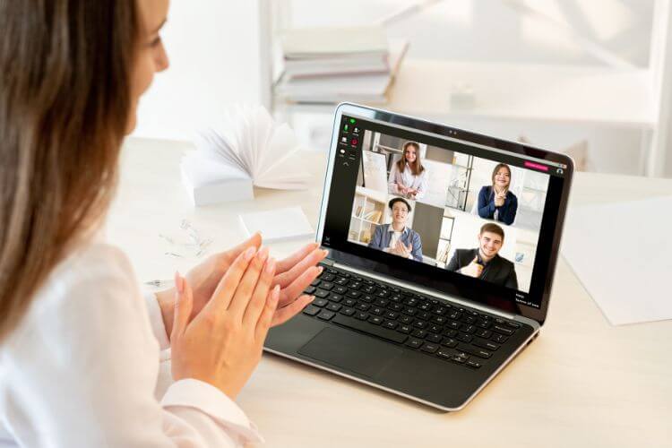 CreaThink Solutions | How Outsourcing Data Entry Helps Australian Real Estate Businesses Scale and Save A woman is seated at her desk with a laptop, clapping in recognition of an Australian VA collaboration.