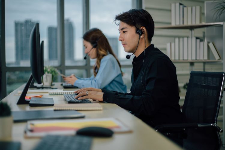 A man and woman work side by side on a computer, discussing their project.