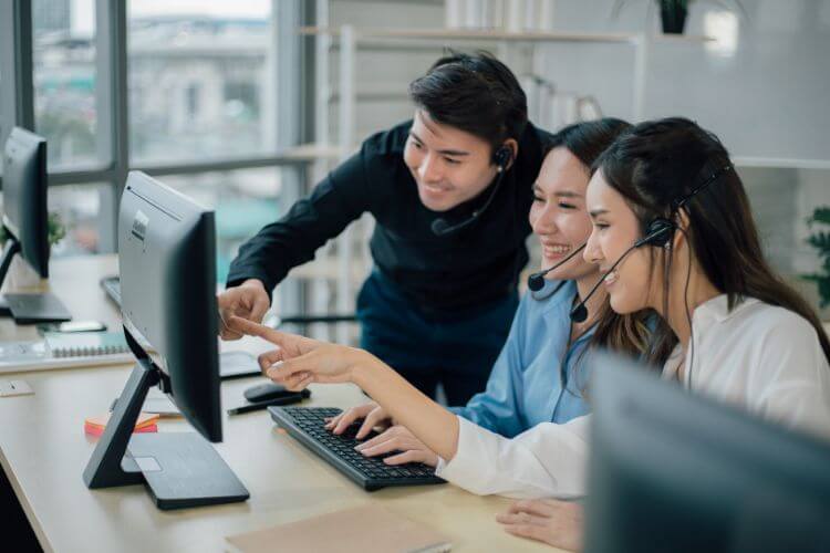 Three professionals engaged in a computer task within an office space.
