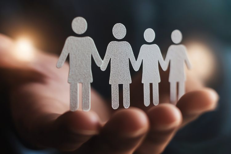 An individual displays paper cutouts representing various people, illustrating the concept of global staffing.