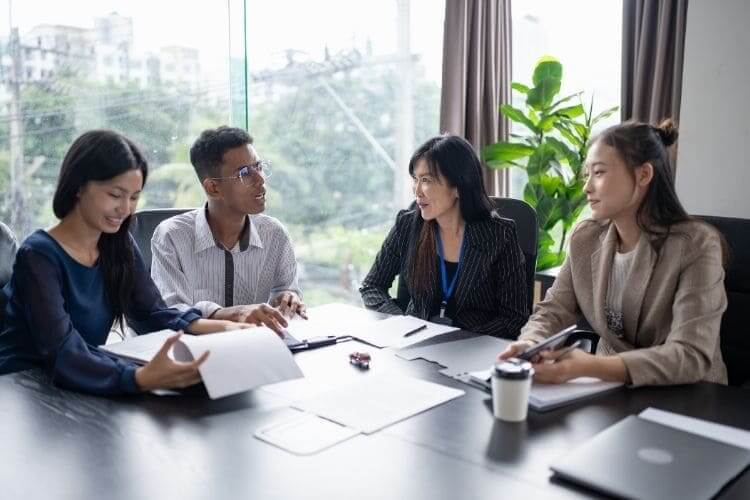 Asian business professionals engaged in a strategic meeting and discussion around a conference table.