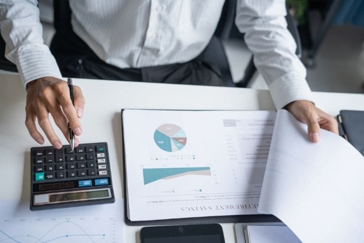 CreaThink Solutions | Outsourcing to the Philippines vs. AI Customer Support Tools: What’s Best for Your Australian Business? Top-down view of printed financial bar charts and business data reports on a desk.