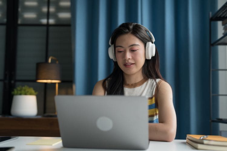Remote worker wearing headphones using laptop at night for virtual assistant or online work