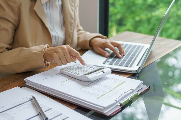 Business professional using calculator and laptop for financial planning and accounting tasks