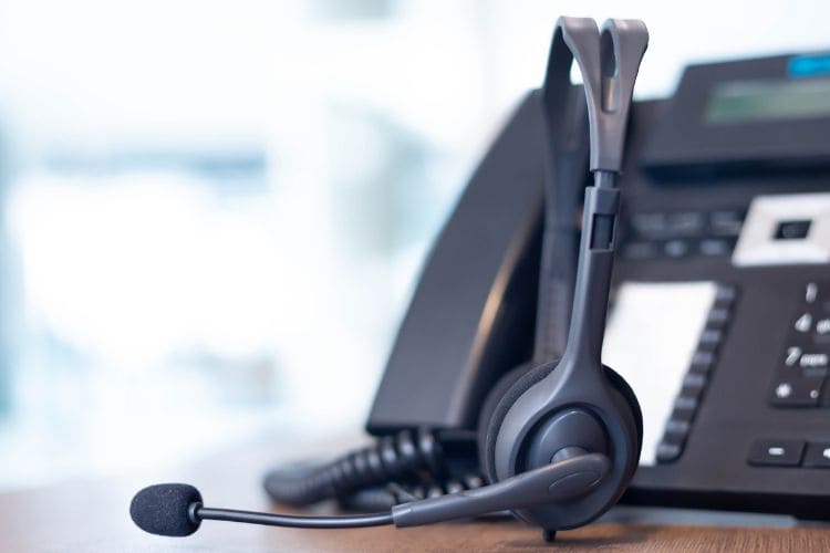 Professional call center headset beside office business phone for customer support services