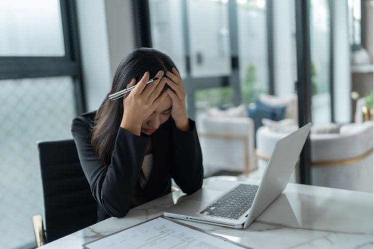 Stressed businesswoman working on laptop dealing with office workload and burnout