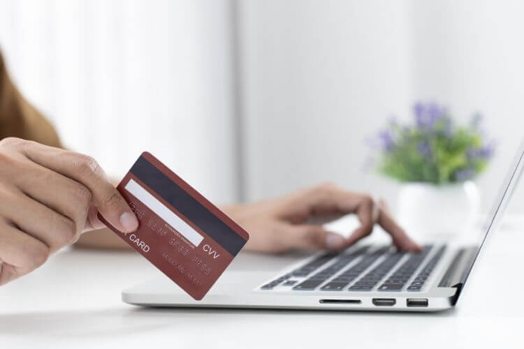 Customer making an online credit card payment for remote business services using a laptop.