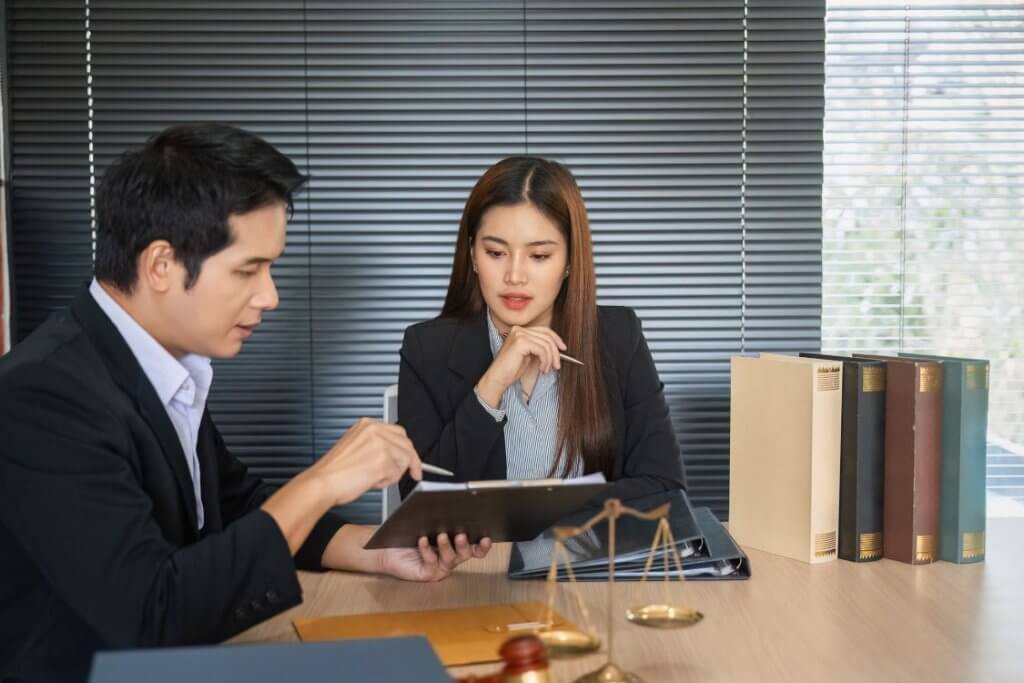CreaThink Solutions | EOR vs Foreign Entity in the Philippines: Which Is Best for US Companies? Administrative assistant reviewing legal documents with a client in a professional office setting.