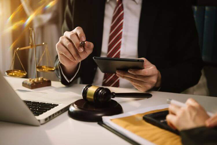 Legal professional reviewing documents with tablet and gavel