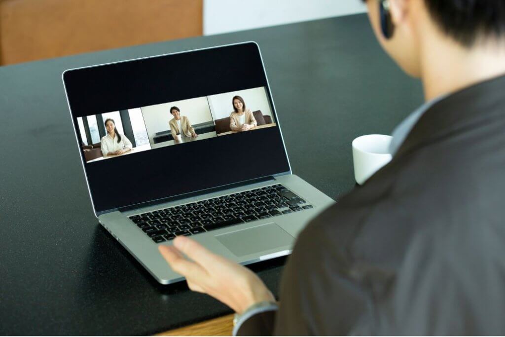 Person attending a remote video meeting on a laptop.