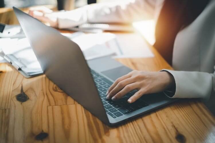 Business professional working on a laptop at a wooden desk.