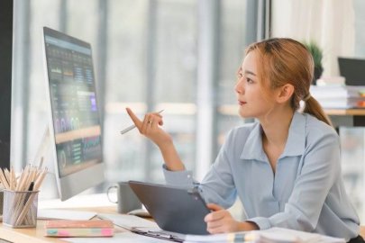 Businesswoman working on a computer with data analytics on screen.