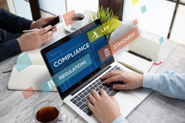 Person using laptop with floating icons for compliance, law, and regulations.