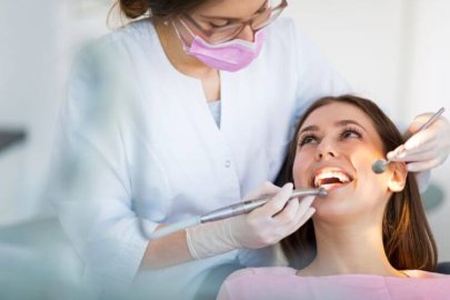 A dentist working on a smiling patient's teeth during a dental procedure.