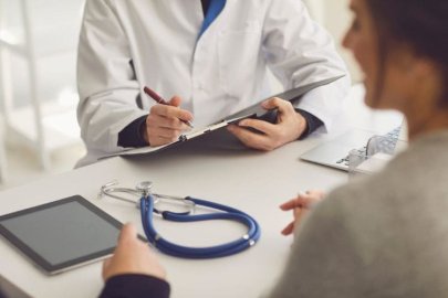 Doctor consulting a patient with a clipboard and stethoscope on the table.