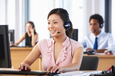 Female customer support agent working on a computer in a busy call center.