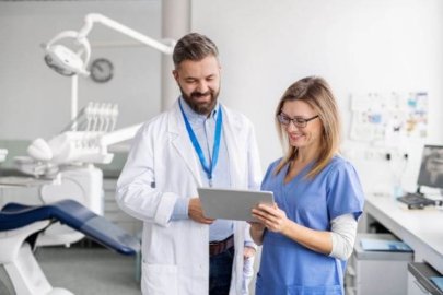 Two healthcare professionals reviewing information on a tablet in a clinic.