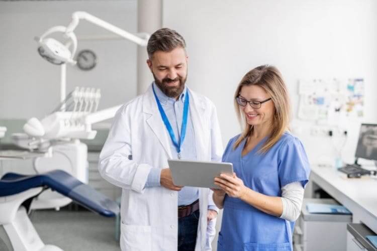 Two healthcare professionals reviewing information on a tablet in a clinic.