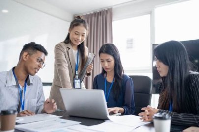 Team of professionals collaborating around a laptop in an office.