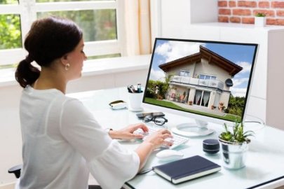 Real estate agent working on a desktop displaying a house image.