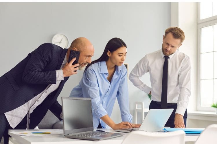 Three colleagues collaborating on a project at a desk.