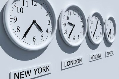 Four wall clocks display different times, labeled in various languages, illustrating time zone management.