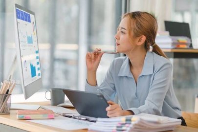 A woman analyzing charts on a computer screen at her desk